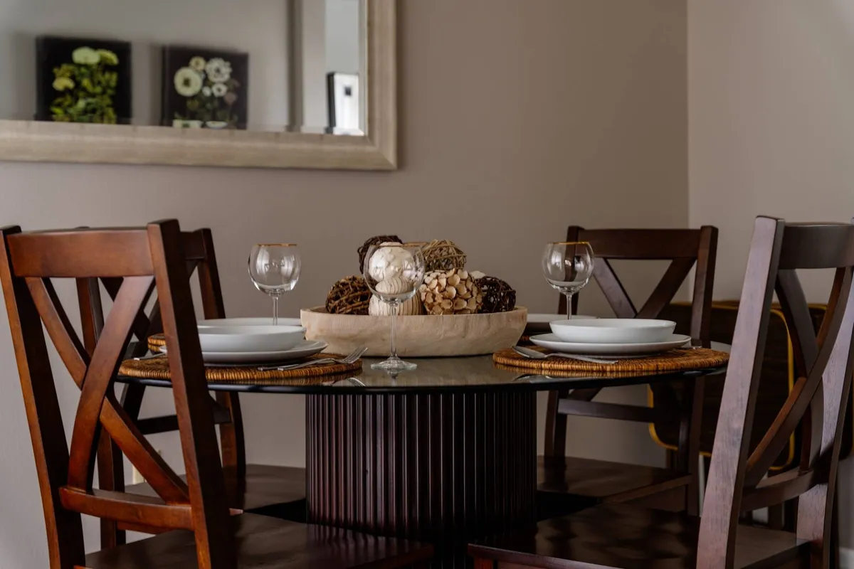 The photo centers on a wooden dining table elegantly set with wine glasses and a decorative bowl, capturing the feel of intimate gatherings and shared meals. The ambient lighting and natural materials evoke warmth and hospitality, hinting at the area's local flavor and the enjoyment of nearby wine tasting experiences.